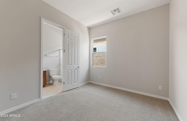 unfurnished bedroom featuring ensuite bath and carpet