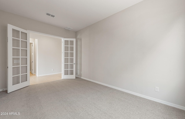 empty room featuring french doors and light colored carpet