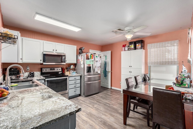 kitchen featuring light stone countertops, appliances with stainless steel finishes, ceiling fan, sink, and white cabinetry