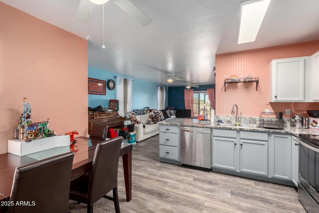 kitchen with light stone countertops, stainless steel appliances, white cabinetry, and sink