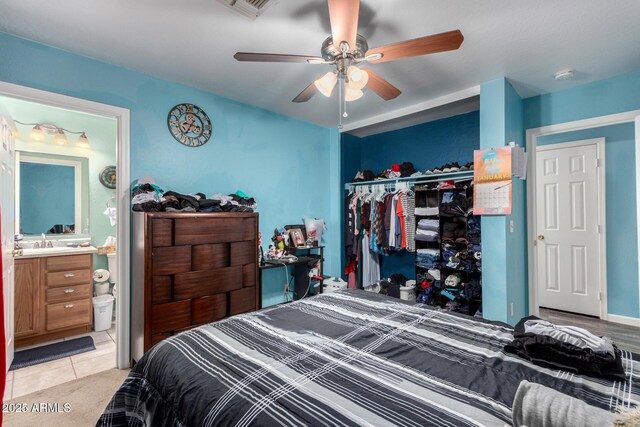 bedroom with ceiling fan, sink, light tile patterned floors, connected bathroom, and a closet