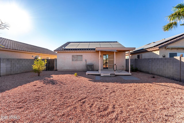 rear view of property with solar panels, cooling unit, and a patio area