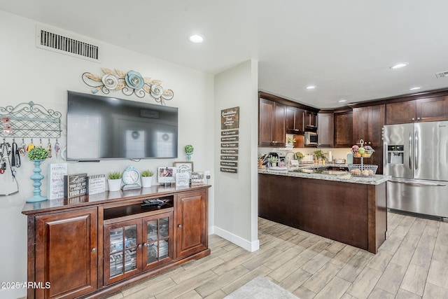 kitchen with visible vents, dark brown cabinets, light wood-type flooring, light stone counters, and stainless steel appliances