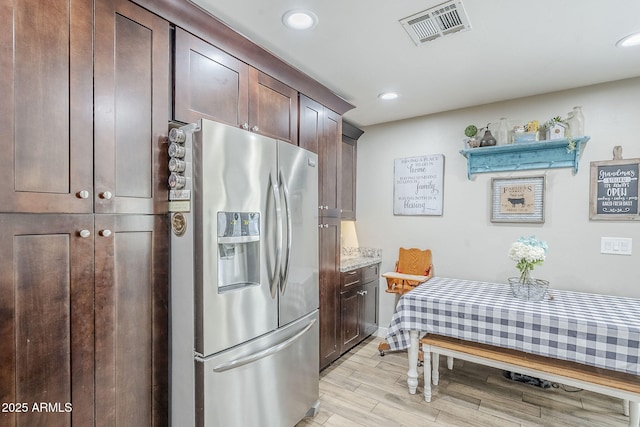 kitchen with visible vents, recessed lighting, dark brown cabinetry, light wood-style floors, and stainless steel fridge