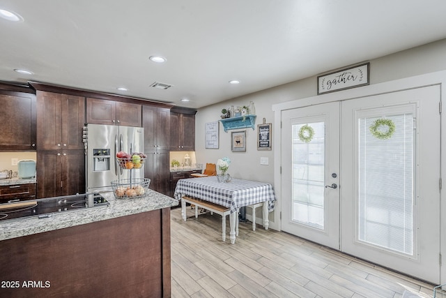 kitchen featuring visible vents, dark brown cabinets, black electric stovetop, french doors, and stainless steel refrigerator with ice dispenser