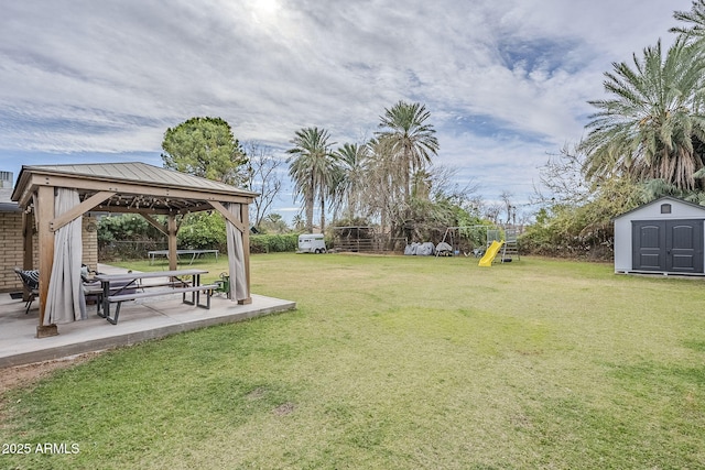 view of yard with a patio, a gazebo, an outdoor structure, a storage shed, and a playground