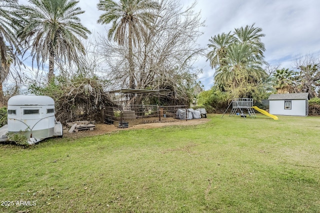 view of yard with an outdoor structure, a playground, and a shed