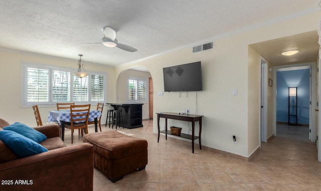 living room featuring crown molding, light tile patterned floors, a textured ceiling, and ceiling fan