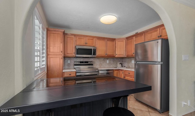 kitchen with appliances with stainless steel finishes, sink, light tile patterned floors, and backsplash