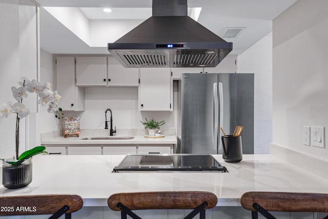 kitchen with a sink, light countertops, island range hood, and freestanding refrigerator