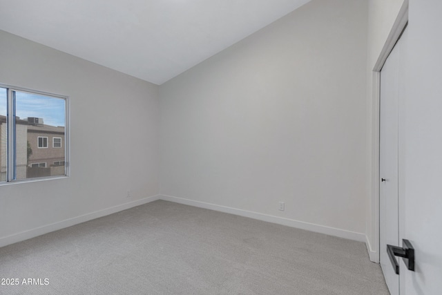 unfurnished bedroom with vaulted ceiling, light colored carpet, and baseboards