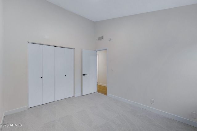 unfurnished bedroom featuring baseboards, carpet floors, a closet, and visible vents