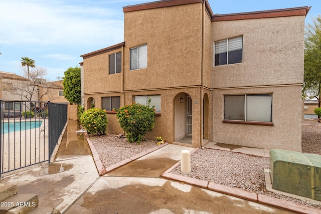 multi unit property with stucco siding, a patio, and fence