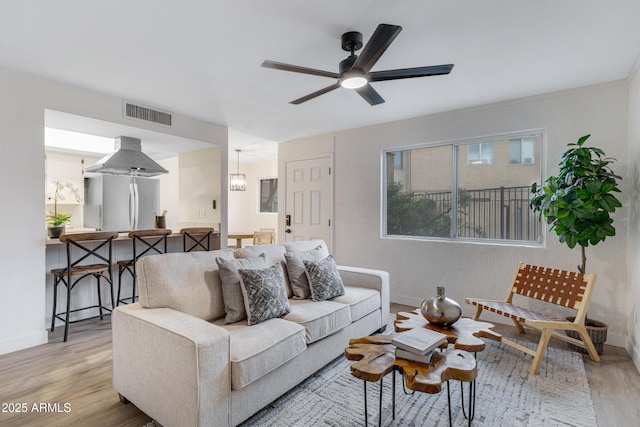 living area featuring ceiling fan, visible vents, baseboards, and wood finished floors