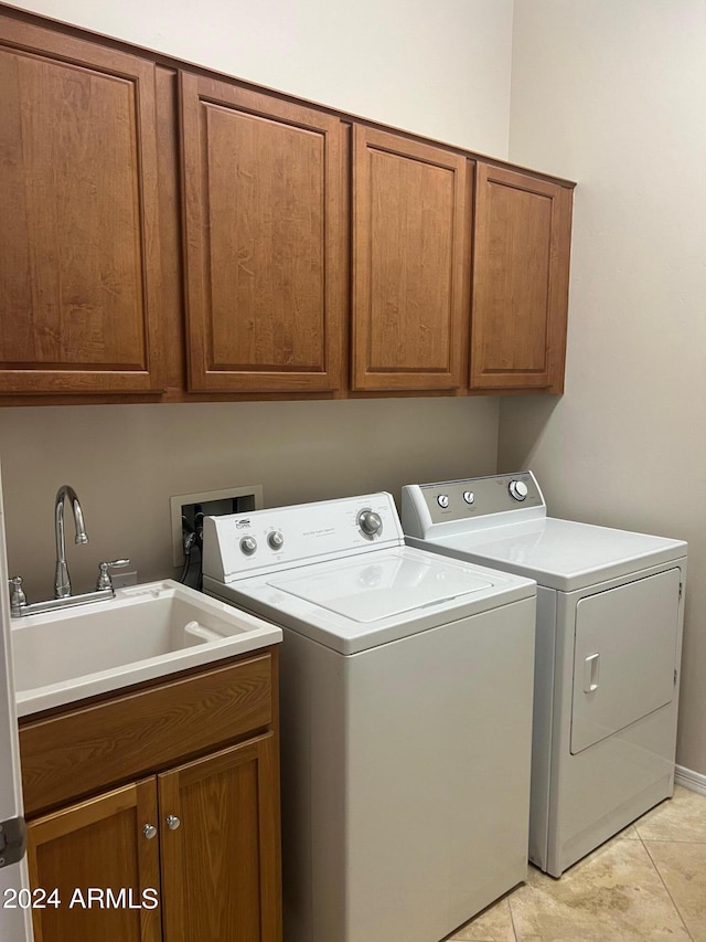 laundry room featuring washing machine and dryer, washer hookup, sink, light tile floors, and cabinets