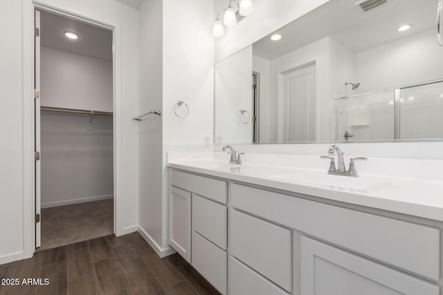 12362 W Marguerite Ave, Avondale, AZ 85323 - bathroom featuring a stall shower, wood finished floors, double vanity, a walk in closet, and recessed lighting