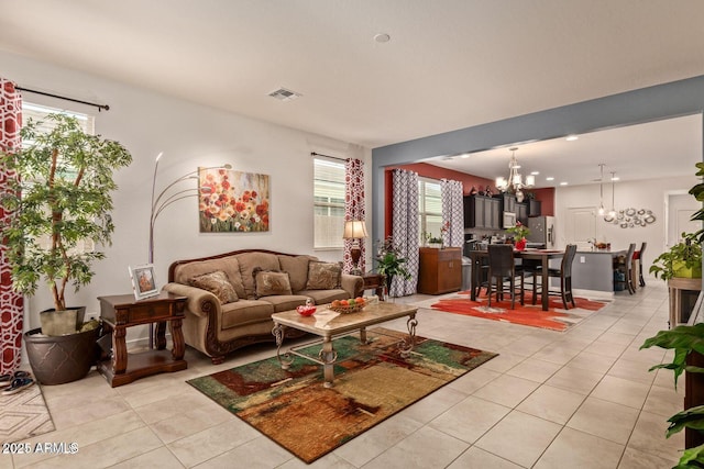 living room with a healthy amount of sunlight, visible vents, a notable chandelier, and light tile patterned floors