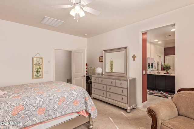 bedroom with light colored carpet, ceiling fan, visible vents, and ensuite bath