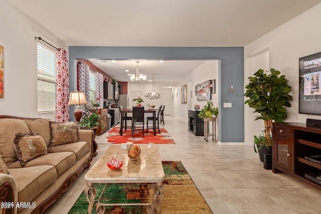 living room featuring an inviting chandelier, light tile patterned floors, and baseboards