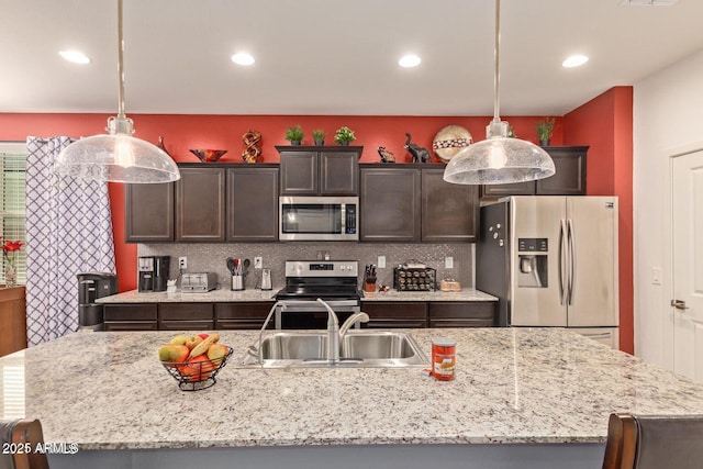 kitchen with appliances with stainless steel finishes, backsplash, a sink, and dark brown cabinetry