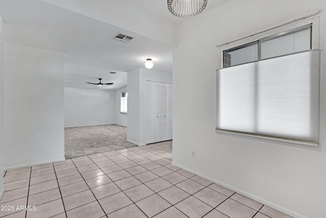 spare room with ceiling fan with notable chandelier and light tile patterned floors