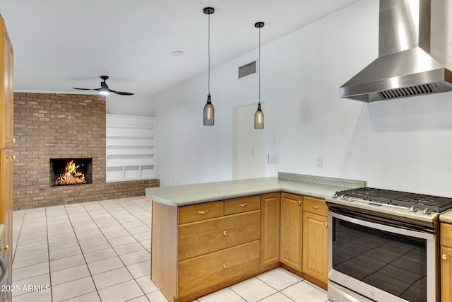 kitchen with stainless steel gas range, ceiling fan, island exhaust hood, built in features, and a brick fireplace