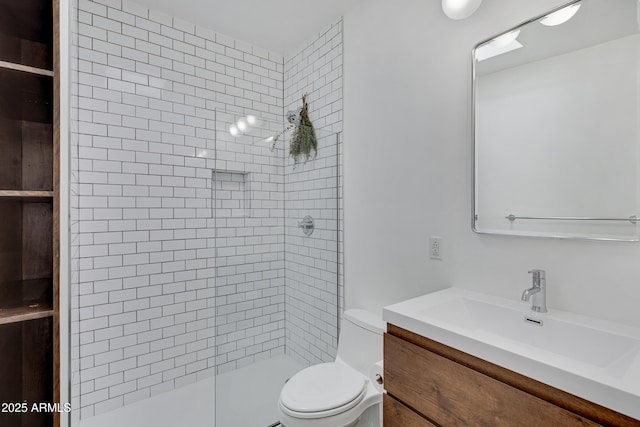 bathroom with toilet, a tile shower, and vanity