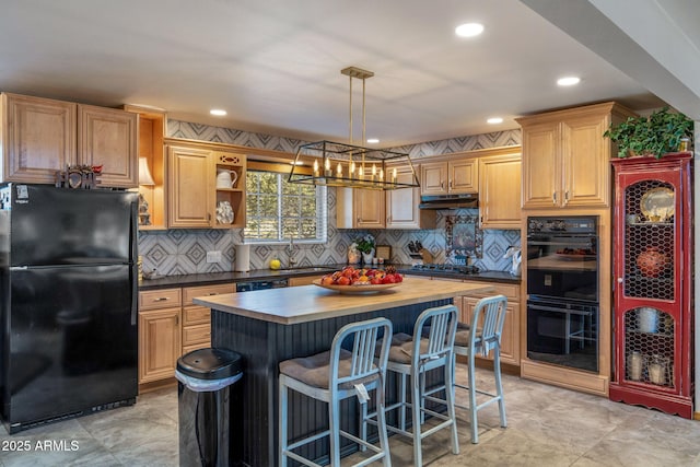 kitchen with pendant lighting, a center island, black appliances, decorative backsplash, and butcher block counters