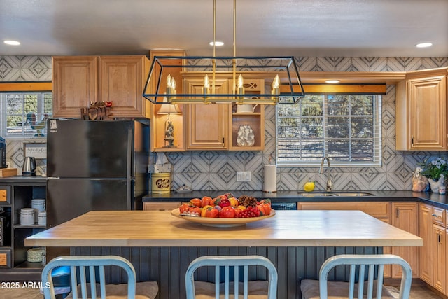 kitchen featuring wood counters, black refrigerator, sink, backsplash, and a breakfast bar area