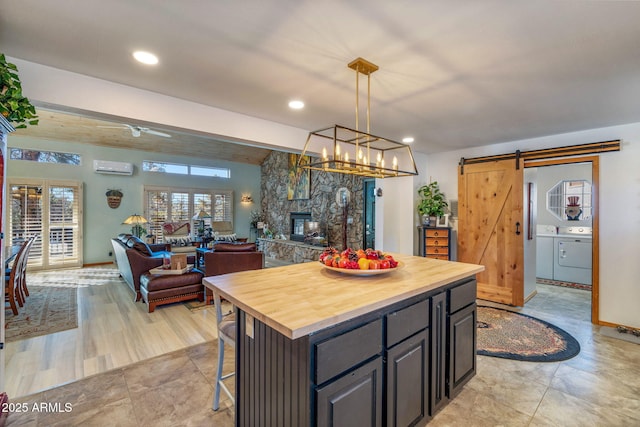 kitchen featuring pendant lighting, wooden counters, a barn door, a kitchen island, and washer and clothes dryer