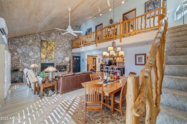 dining area featuring a stone fireplace, wood ceiling, ceiling fan with notable chandelier, high vaulted ceiling, and light hardwood / wood-style floors