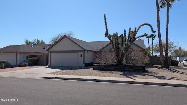 view of front of house featuring an attached garage, fence, board and batten siding, and driveway