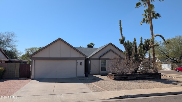 view of front of property with an attached garage, concrete driveway, and fence