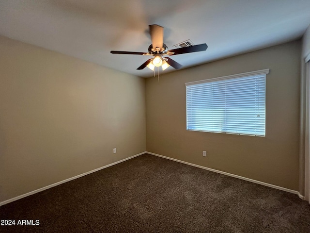 spare room featuring dark carpet and ceiling fan