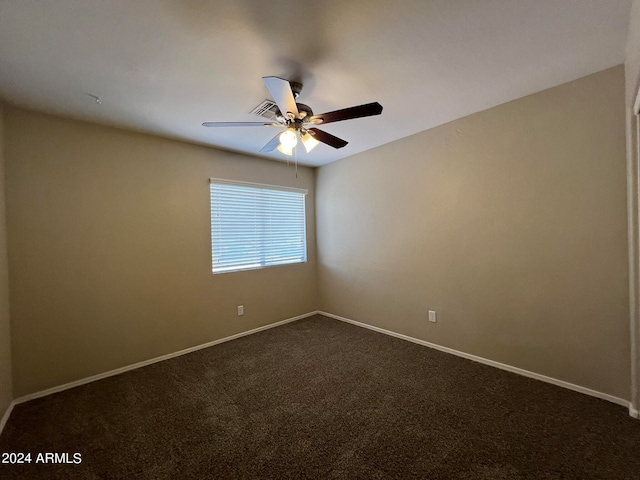 unfurnished room with dark colored carpet and ceiling fan