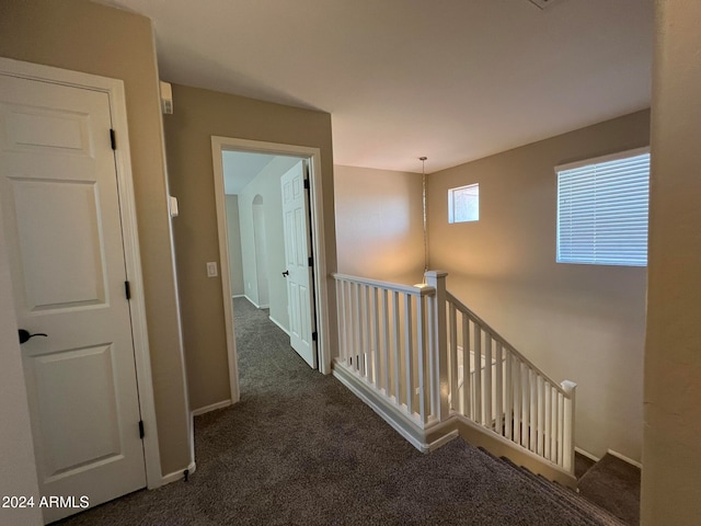 hall featuring dark colored carpet