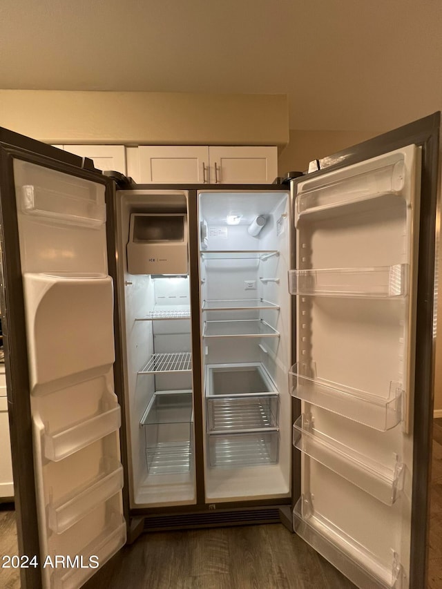 interior details featuring dark wood-type flooring, white cabinets, and refrigerator