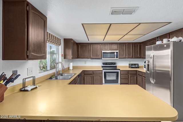 kitchen with visible vents, a sink, stainless steel appliances, dark brown cabinetry, and light countertops