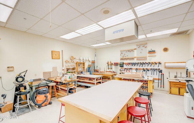 interior space with a drop ceiling, a kitchen breakfast bar, and visible vents