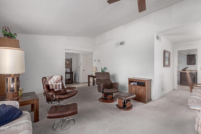 living area featuring visible vents, lofted ceiling, light colored carpet, and a textured ceiling