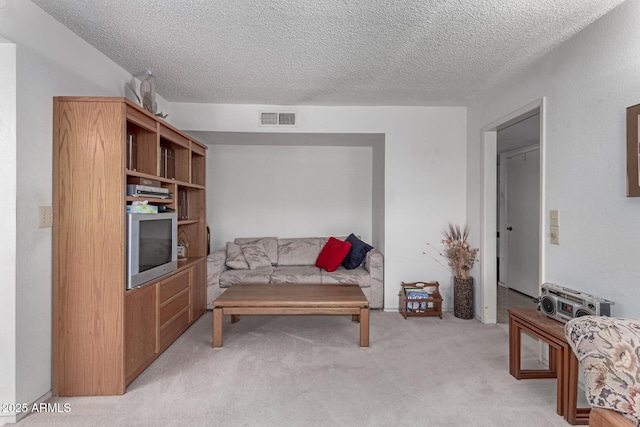 living area with visible vents, light colored carpet, and a textured ceiling