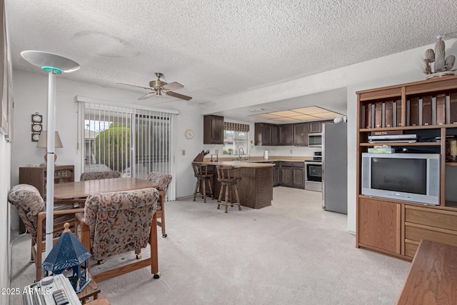 dining area featuring plenty of natural light, a textured ceiling, light carpet, and ceiling fan