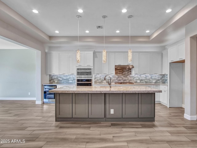 16881 W Merrell St, Goodyear, AZ 85395 - kitchen featuring appliances with stainless steel finishes, beverage cooler, white cabinetry, baseboards, and light wood-style floors