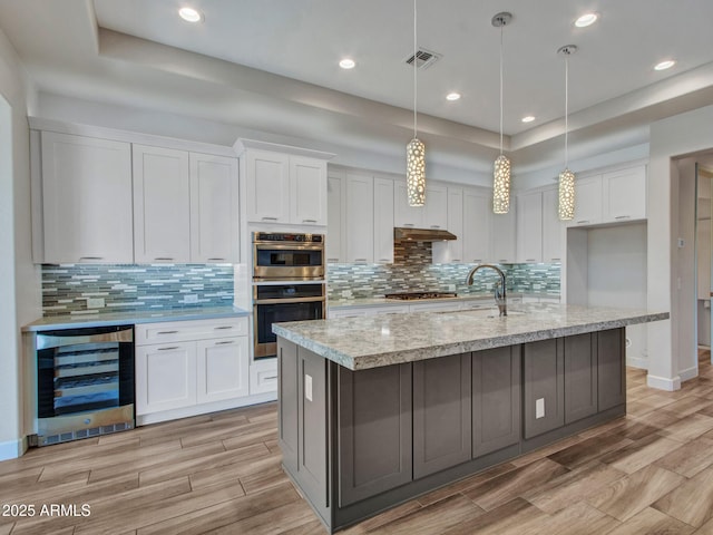 16881 W Merrell St, Goodyear, AZ 85395 - kitchen featuring beverage cooler, appliances with stainless steel finishes, white cabinets, under cabinet range hood, and recessed lighting