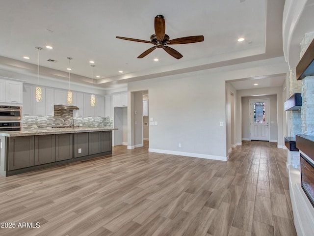 16881 W Merrell St, Goodyear, AZ 85395 - kitchen featuring white cabinetry, ceiling fan, a raised ceiling, a fireplace, and recessed lighting