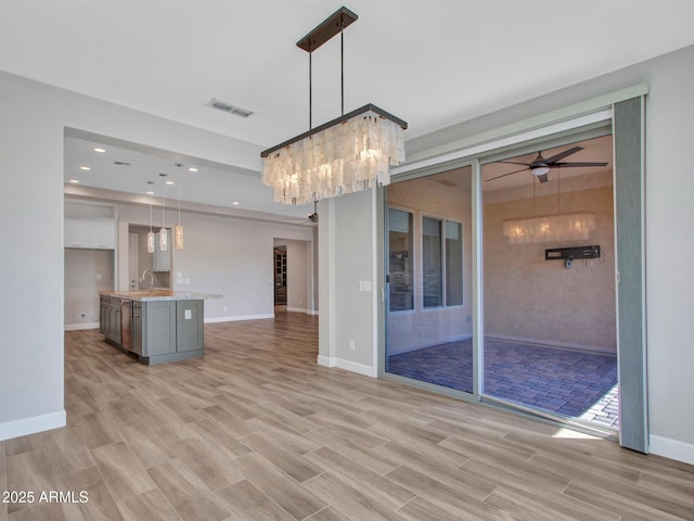 16881 W Merrell St, Goodyear, AZ 85395 - kitchen with open floor plan, a ceiling fan, light countertops, light wood finished floors, and hanging light fixtures