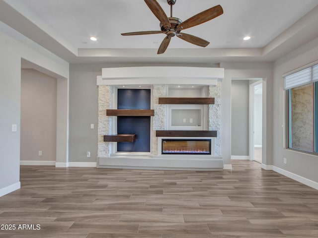 16881 W Merrell St, Goodyear, AZ 85395 - unfurnished living room with a fireplace, a tray ceiling, wood finished floors, a ceiling fan, and recessed lighting