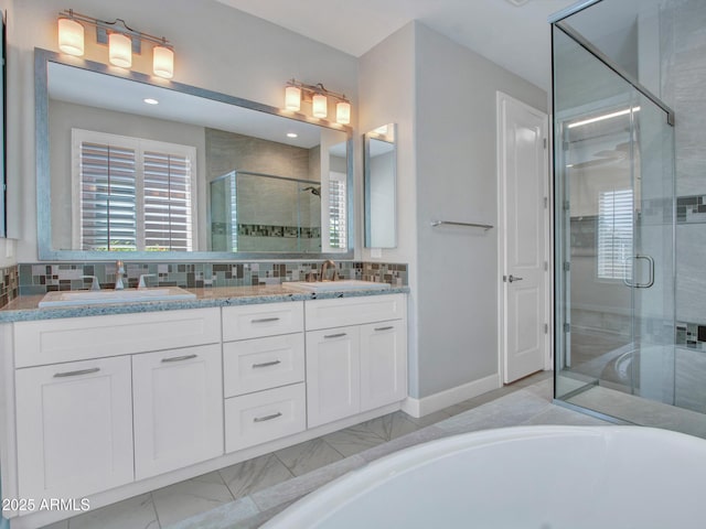 16881 W Merrell St, Goodyear, AZ 85395 - full bath featuring a stall shower, double vanity, decorative backsplash, a tub with jets, and baseboards