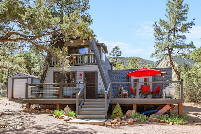 4872 N Trails End Dr, Pine, AZ 85544 - view of front of house featuring a deck, a storage unit, an outdoor structure, a shingled roof, and a balcony
