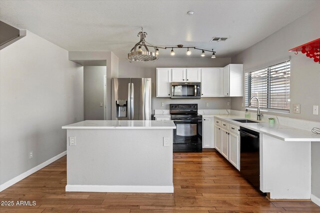 7500 E Deer Valley Rd Unit 54, Scottsdale, AZ 85255 - kitchen with black appliances, a sink, a center island, wood finished floors, and white cabinetry